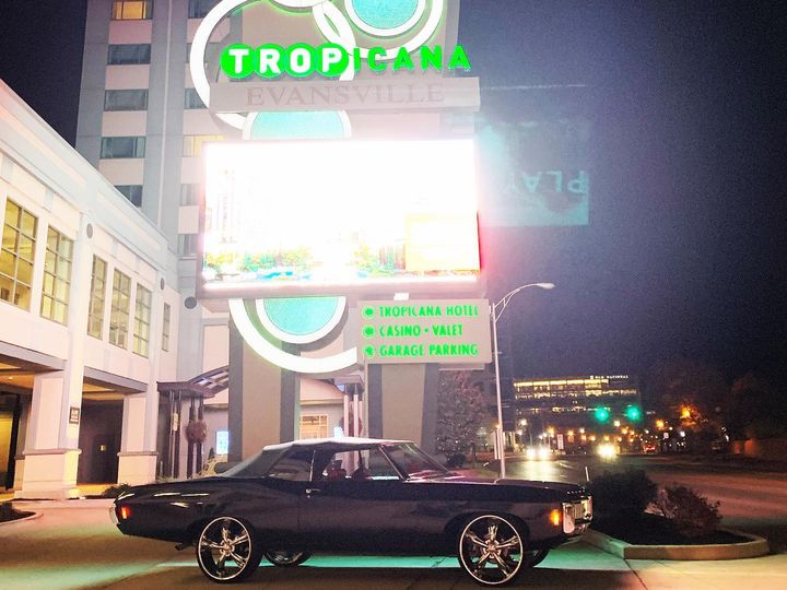 Black Chevy Impala convertible at night beneath the lit Tropicana Evansville sign
